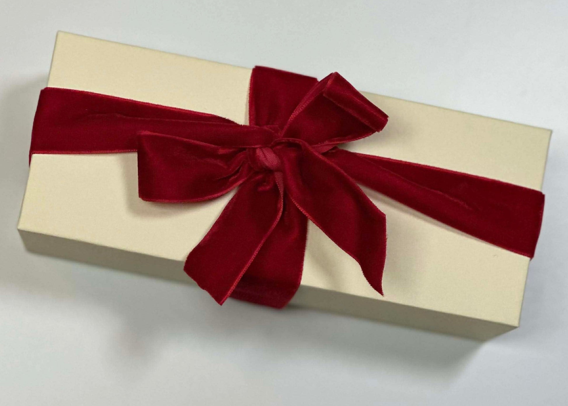 Beige gift box, filled with luxury mini candles with a red ribbon on a light background. 