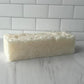 Block of soap on a white surface with a tiled wall background
