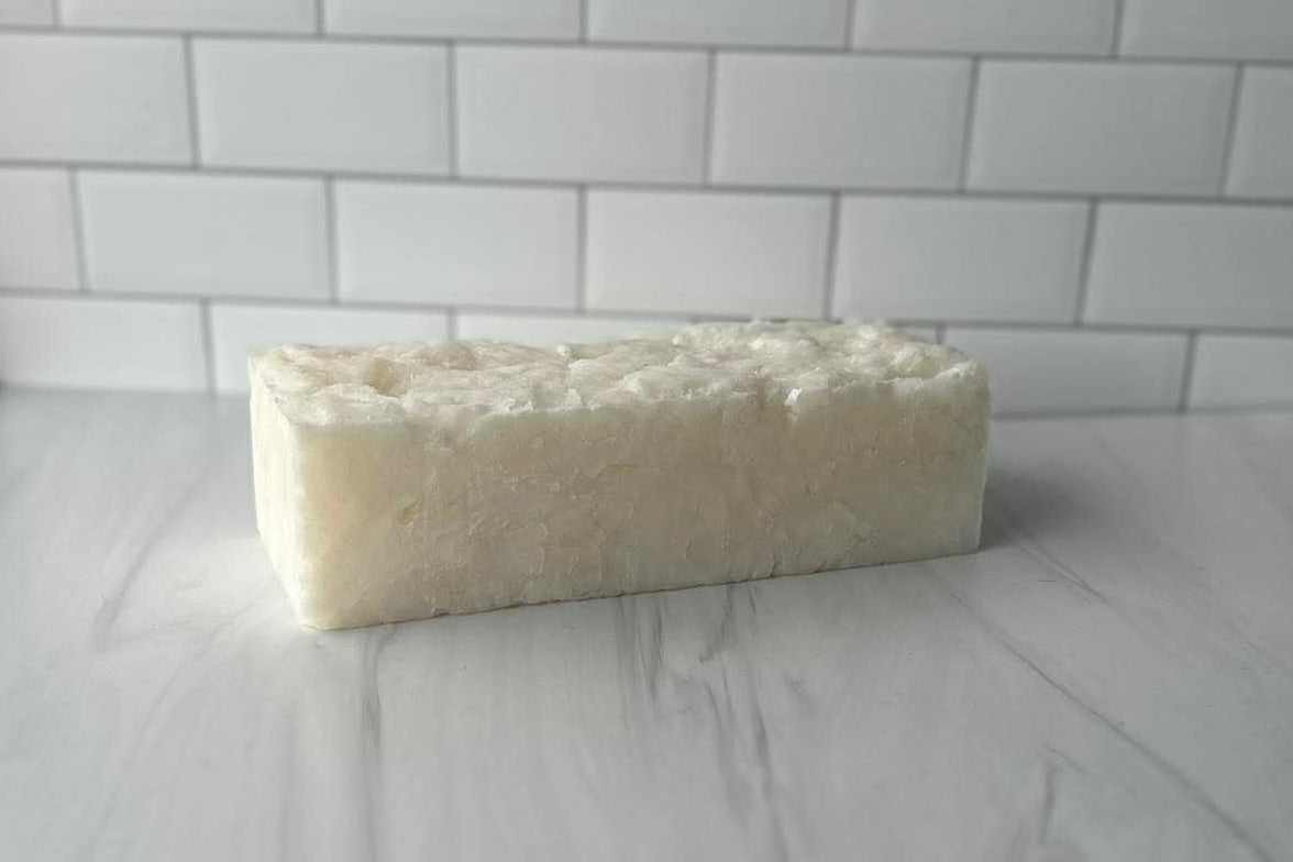 Block of soap on a white surface with a tiled wall background